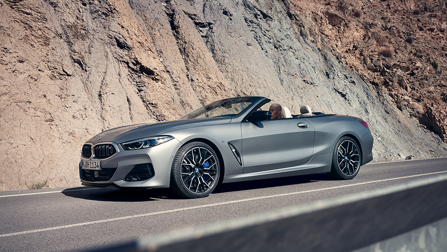 BMW 8 Series Convertible G14 LCI Facelift 2022 BMW Individual Frozen Pure Grey metallic side view with open softtop driving along mountain wall
