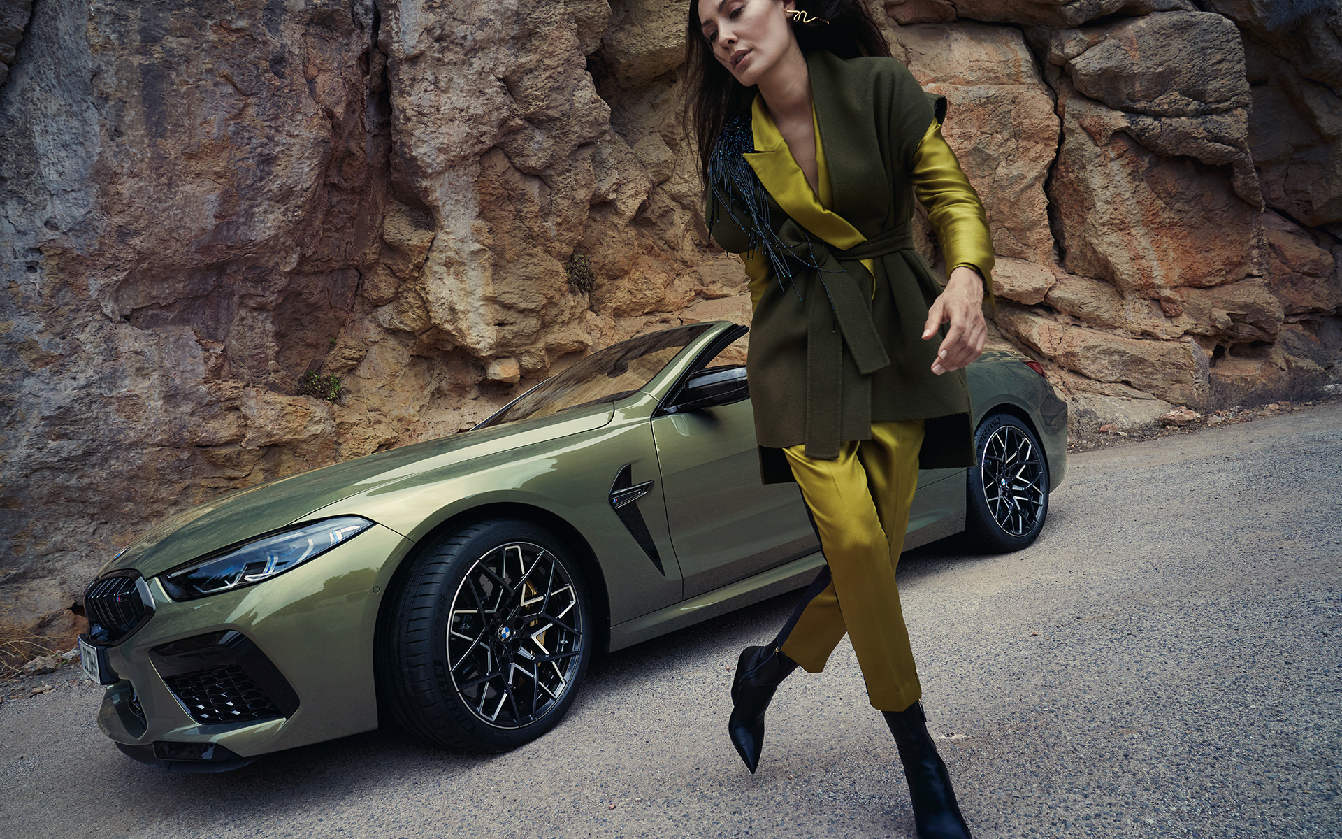 BMW M8 Competition Convertible F91 LCI Facelift 2022 BMW Individual Brass metallic three-quarter front view standing in stony terrain with female model