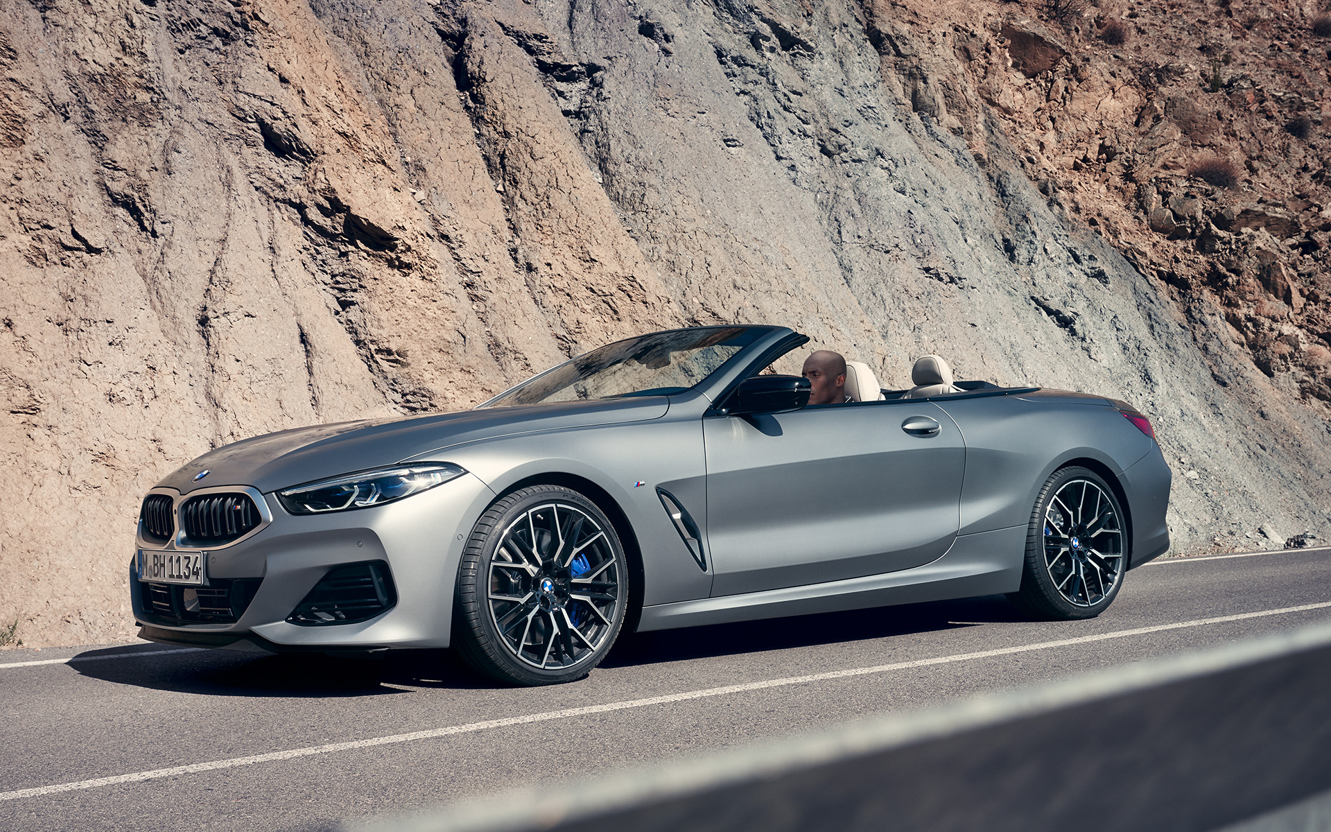 BMW M850i xDrive Convertible G14 LCI Facelift 2022 BMW Individual Frozen Pure Grey metallic three quarter front view driving in front of cliff face