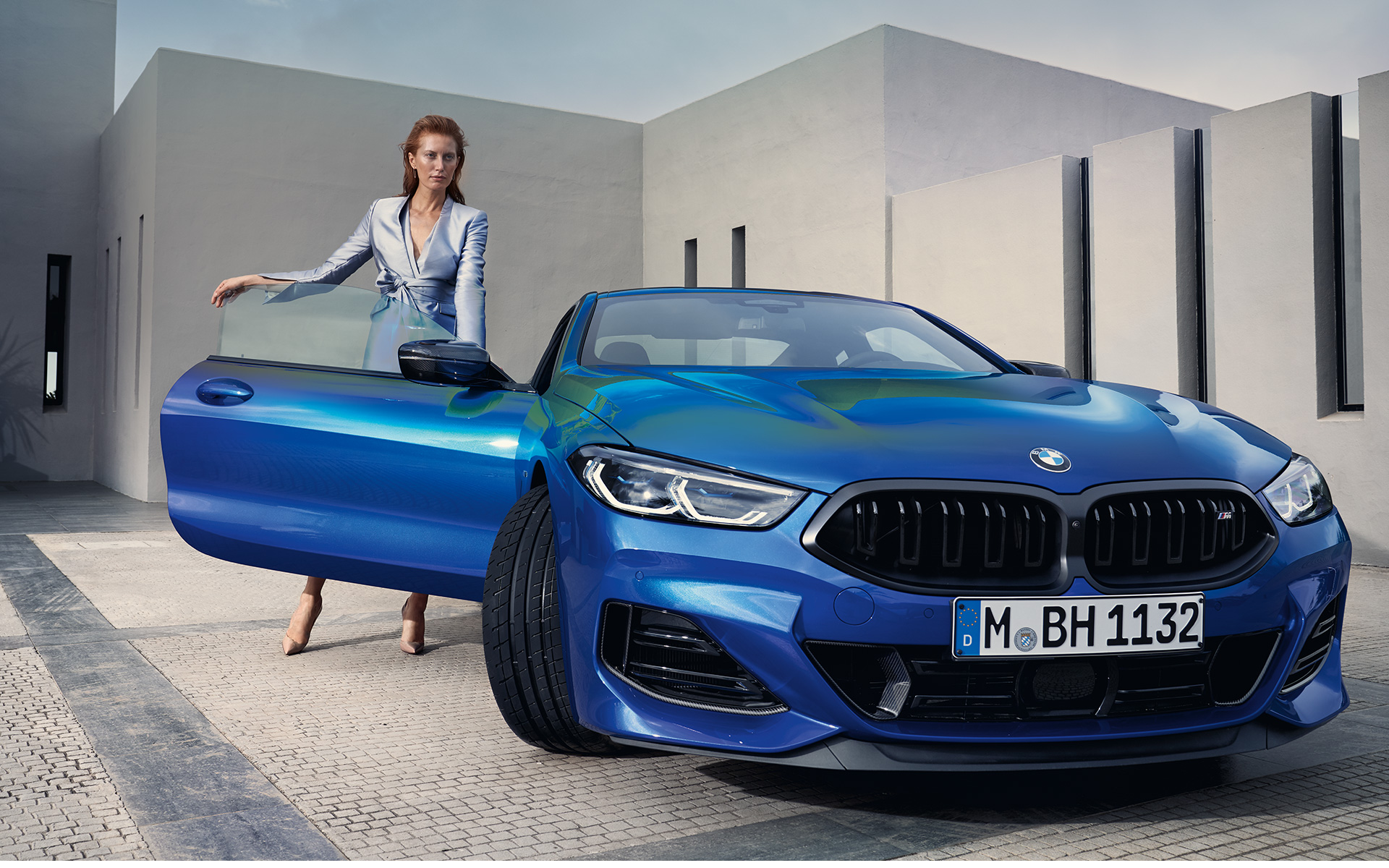 BMW M850i xDrive Coupé G15 LCI Facelift 2022 M Portimao Blue metallic front view standing with female model in open front door