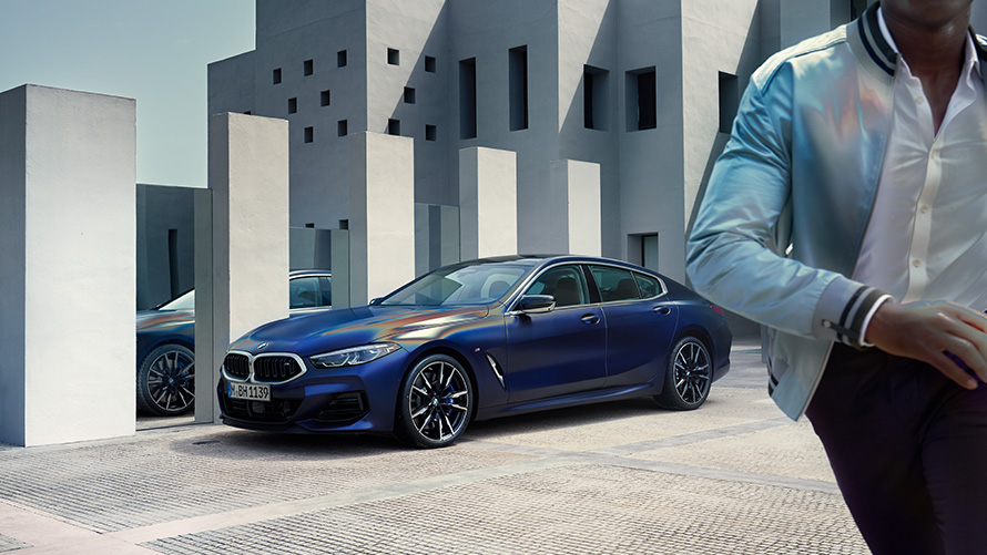 BMW M850i xDrive Gran Coupé G16 LCI Facelift 2022 BMW Individual Frozen Tanzanite Blue metallic three-quarter front view standing with male model in foreground