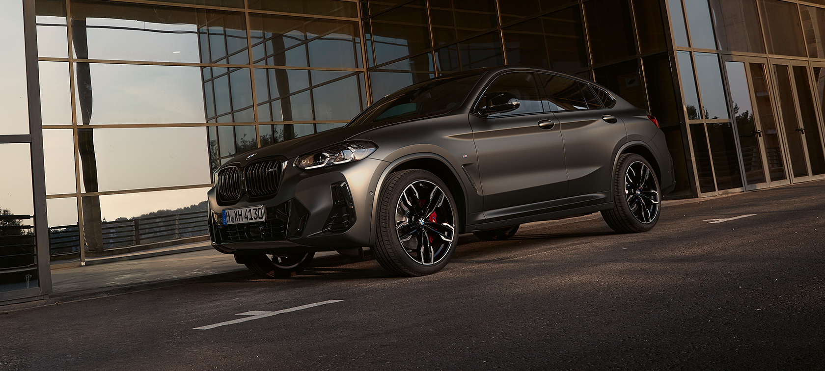 BMW X4 M40i G02 LCI 2021 Facelift three-quarter front view in front of glass facade
