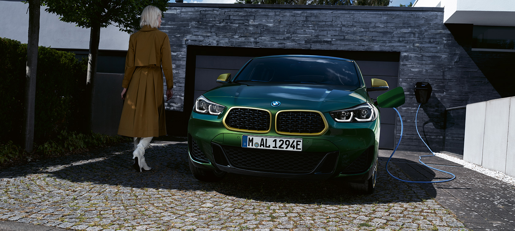 Front view in charging situation with model on left BMW X2 F39 Sanremo Green metallic