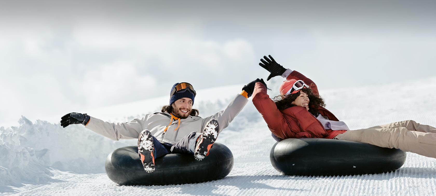 Original BMW Accessories and BMW Service for autumn and winter Woman and man laughing on toboggan tyres in snow